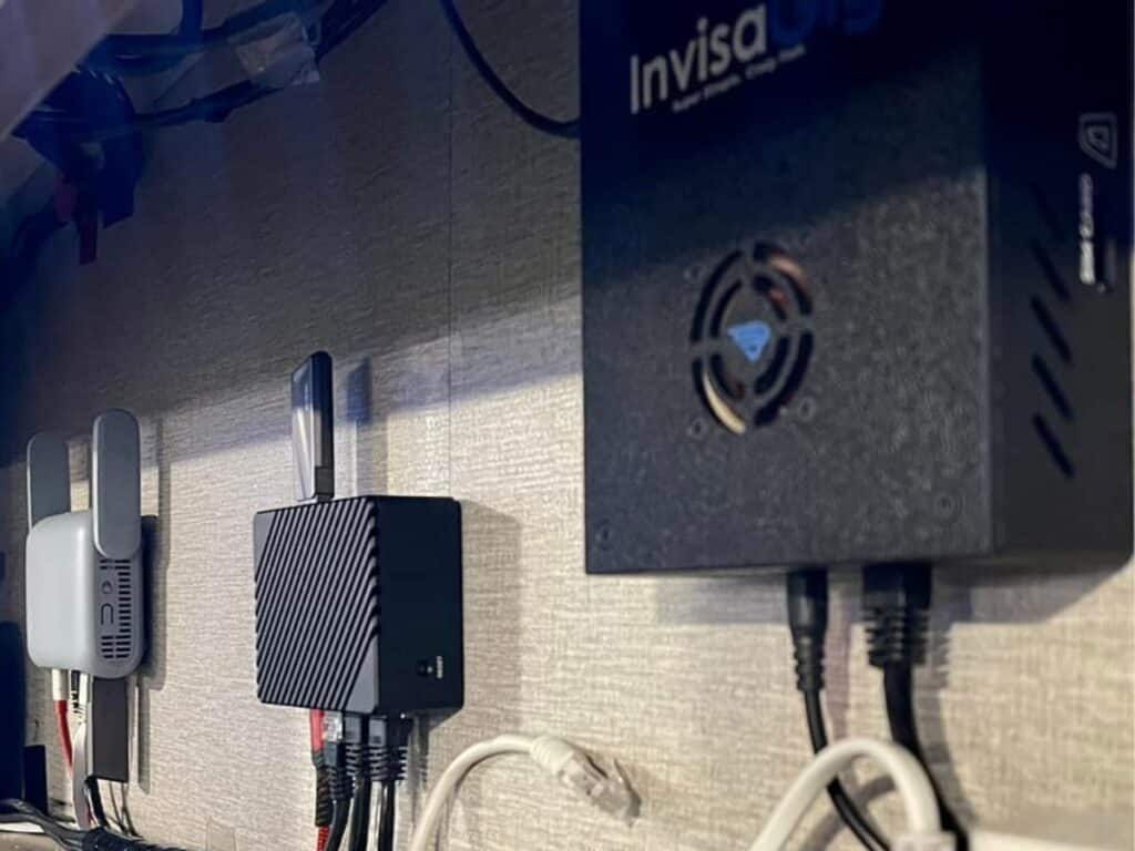 Customer submitted photo. InvisaGig install in aan RV space, showing the invisagig, a router and a wifi router, all mounted to a wall and wired together.