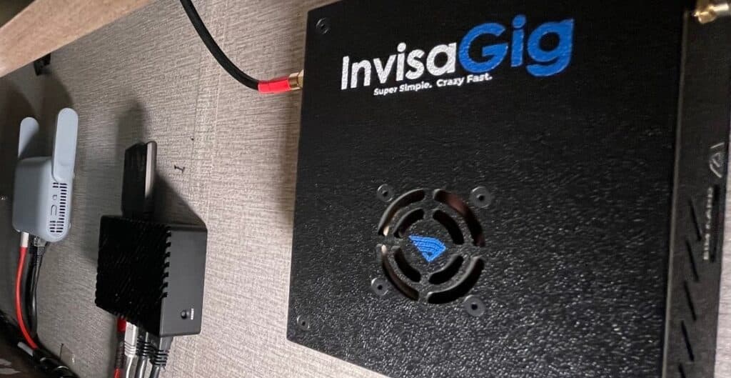 Customer submitted photo. InvisaGig install in an RV space, showing the invisagig, a router and a wifi router, all mounted to a wall and wired together.