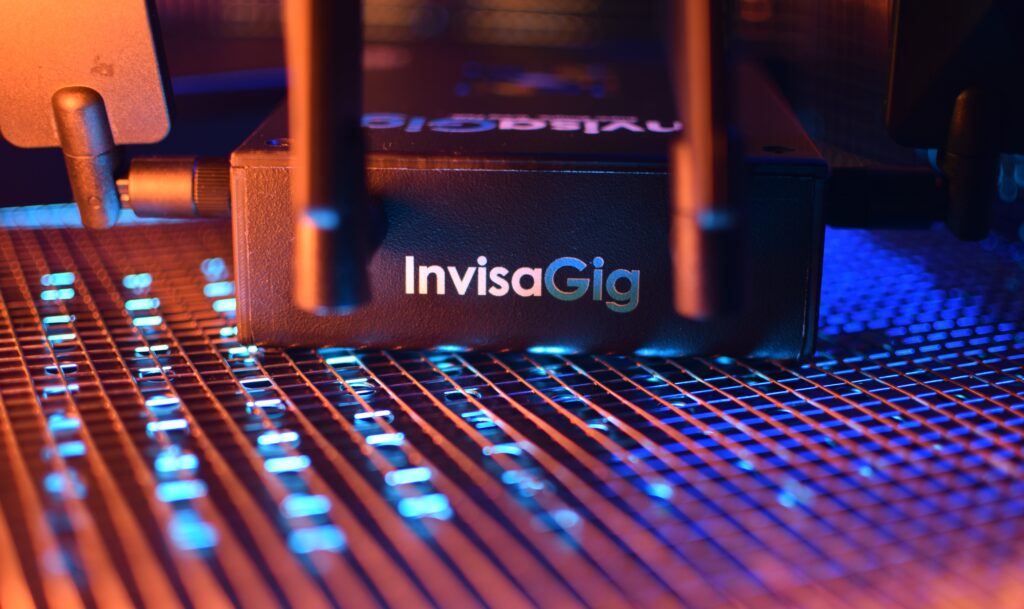 The product logo on the side of the InvisaGig 5G modem housing is shown in a tightly-zoomed product showcase photo, with a technology and connectivity motif in the background to inspire thoughts of internet solutions.